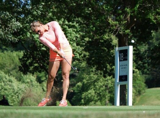 Golfer taking divot from tee